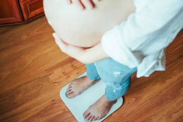 Image of woman weighing herself and experiencing weight gain through pregnancy Sighthill